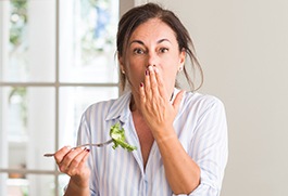 Woman with lost dental crown covering her mouth