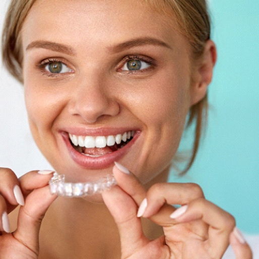 Smiling woman holding teeth whitening trays