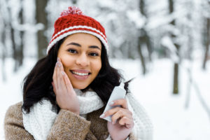 Young woman touching cheek in winter forest