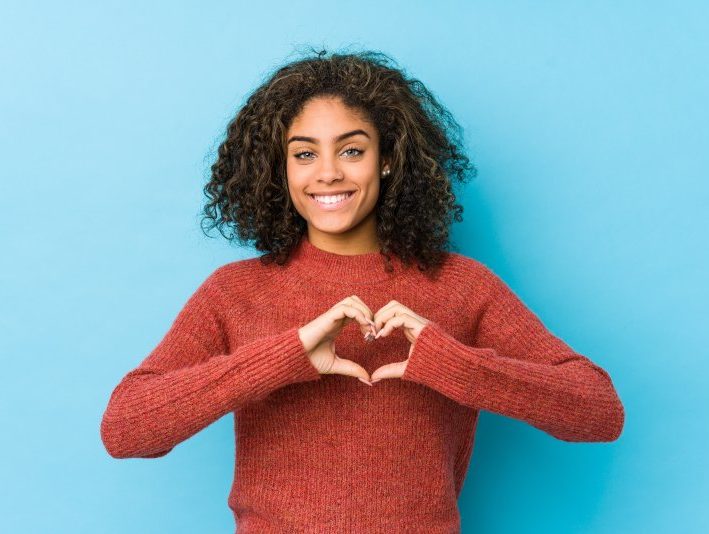 person smiling and making a heart with their hands