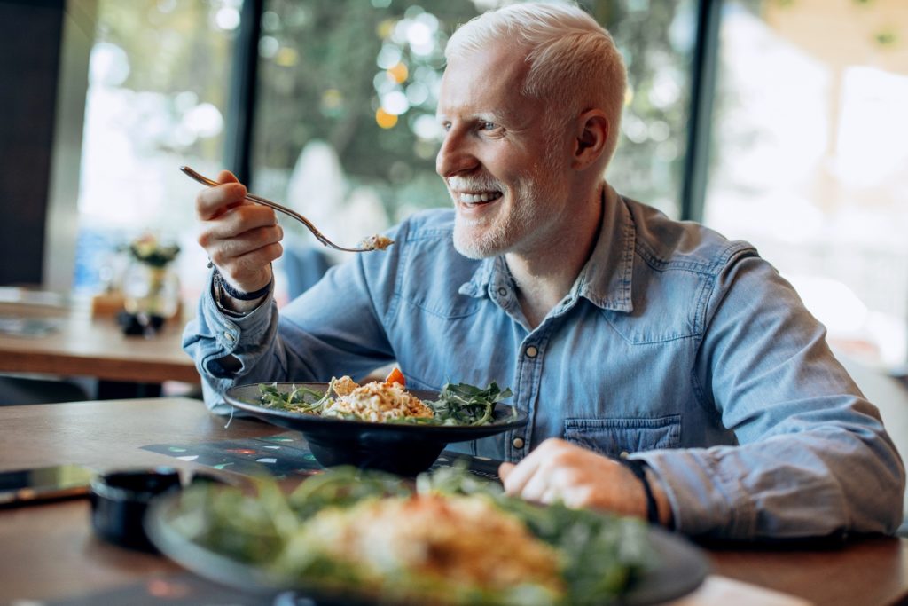 Mature man smiling while eating lunch at restaurant